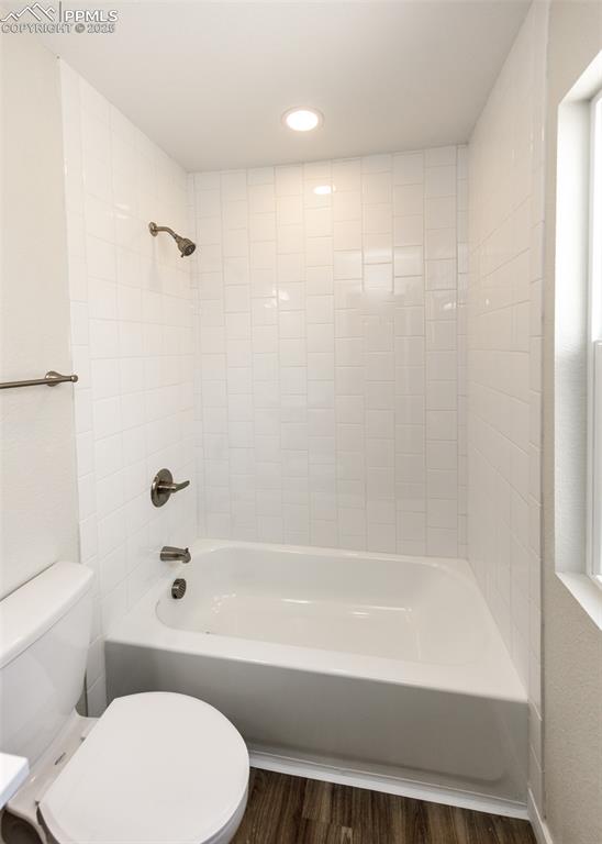 Bathroom featuring  shower combination, dark wood-style flooring, and recessed lighting