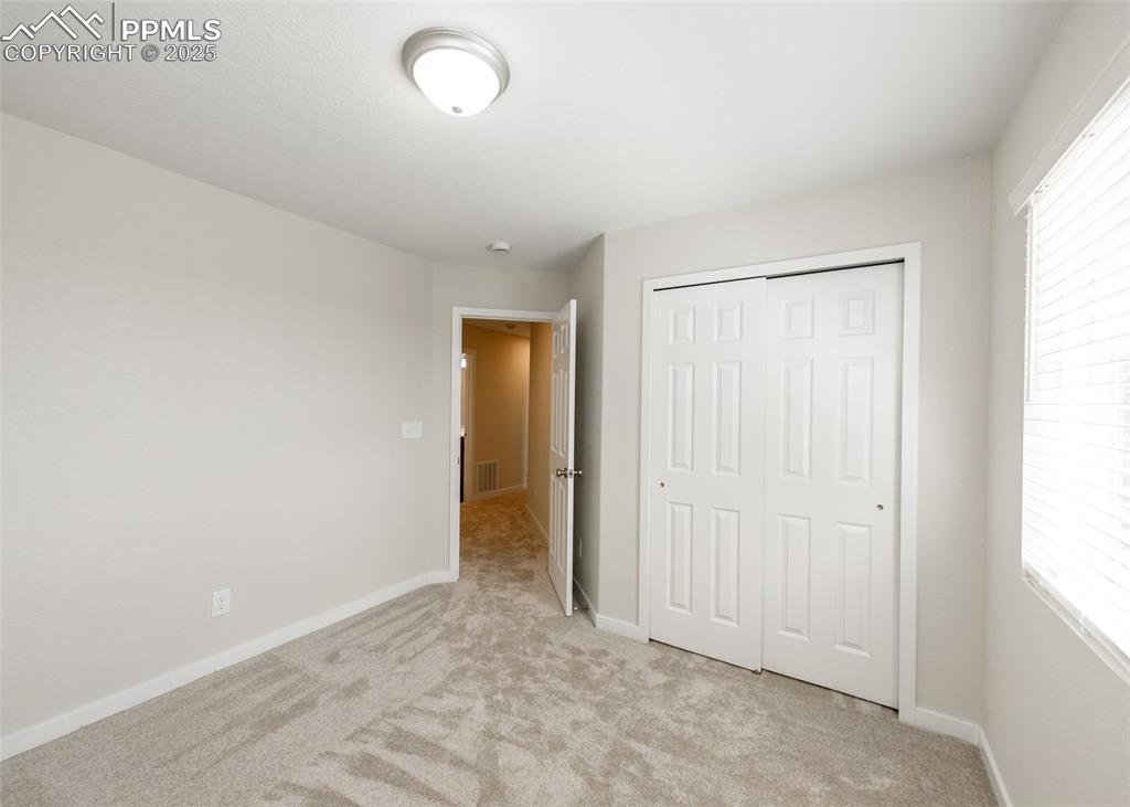 Unfurnished bedroom with light colored carpet and a closet