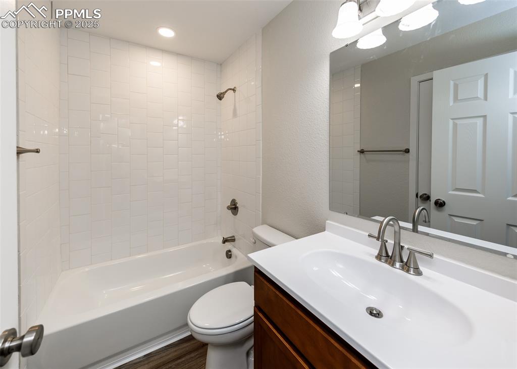 Bathroom with  shower combination, vanity, a textured wall, and recessed lighting