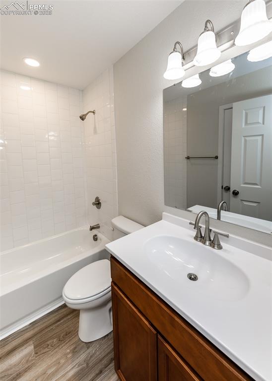 Full bathroom with shower / bath combination, vanity, light wood finished floors, a textured wall, and recessed lighting
