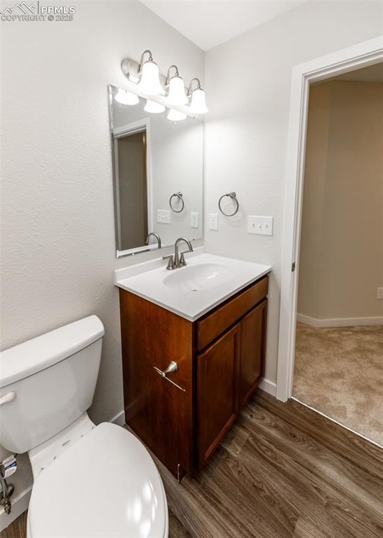 Half bathroom featuring vanity and dark wood finished floors