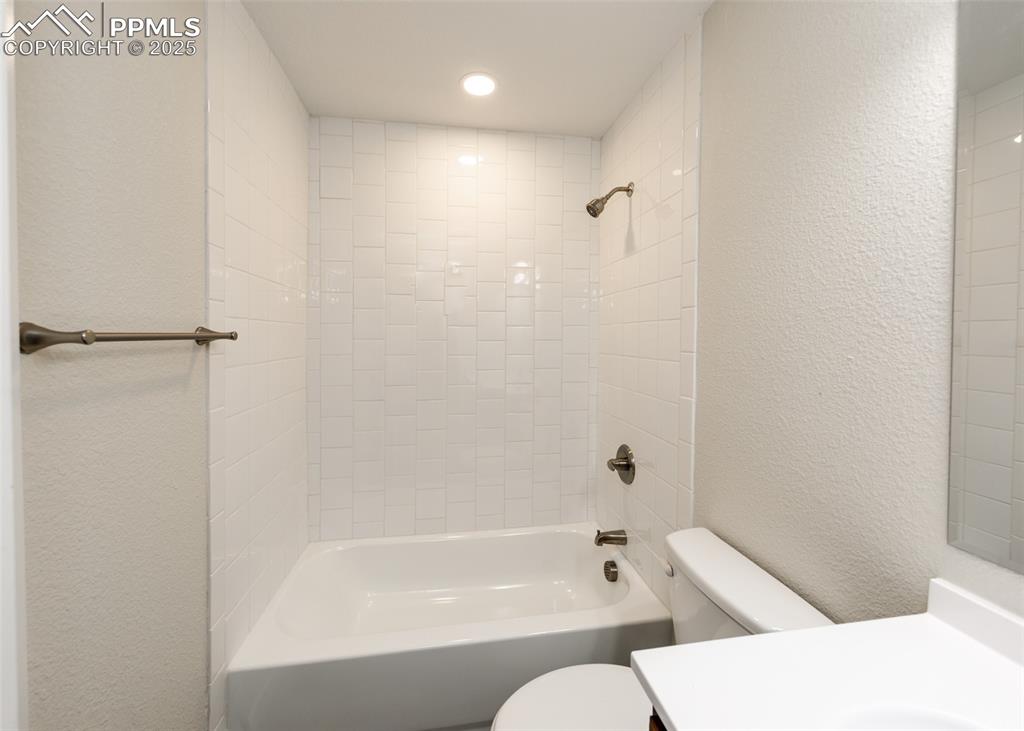 Full bathroom featuring a textured wall, vanity, and  shower combination