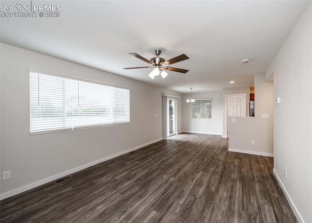 Spare room featuring dark wood-style flooring, a chandelier, and ceiling fan