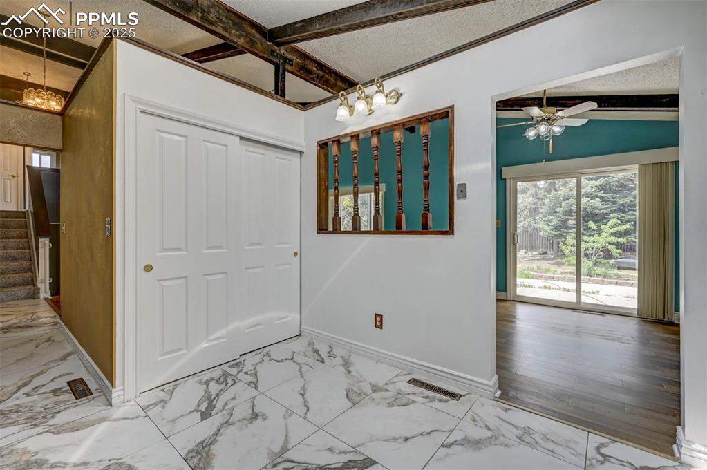 Entrance foyer with a chandelier, marble finish flooring, ceiling fan, stairway, and a textured ceiling