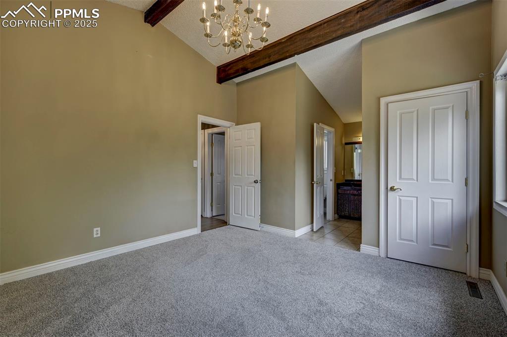 Unfurnished bedroom featuring light carpet, a chandelier, and ensuite bath