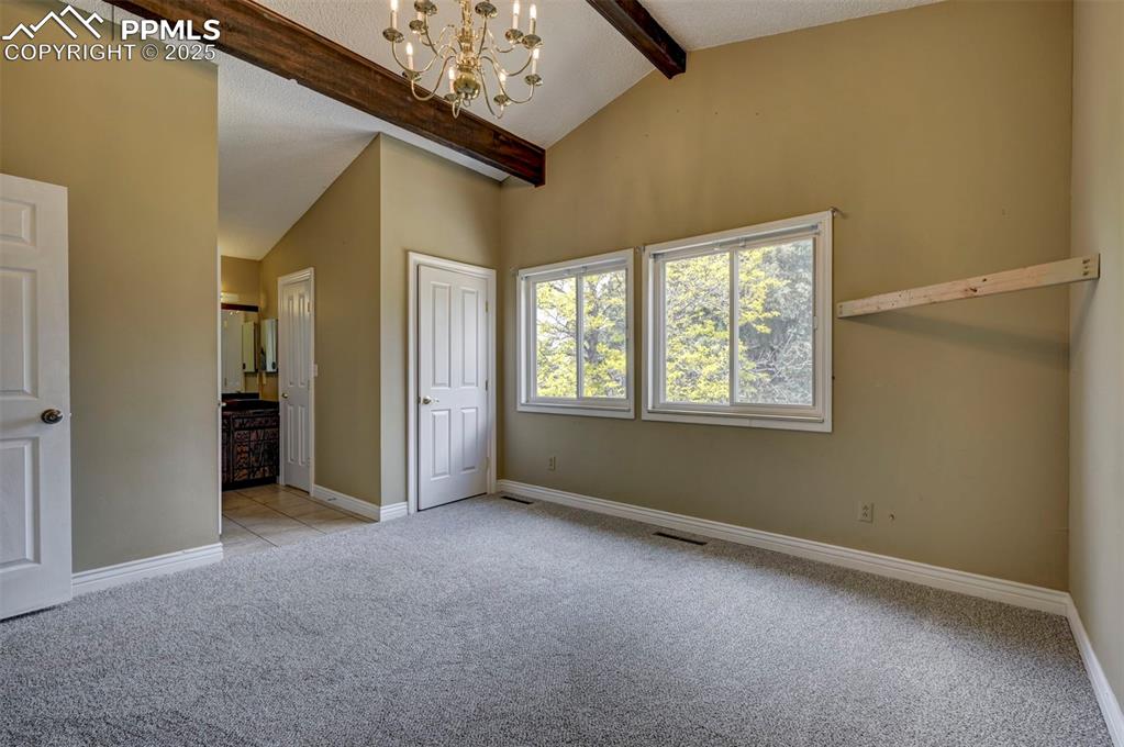 Unfurnished bedroom with light carpet, a chandelier, and connected bathroom