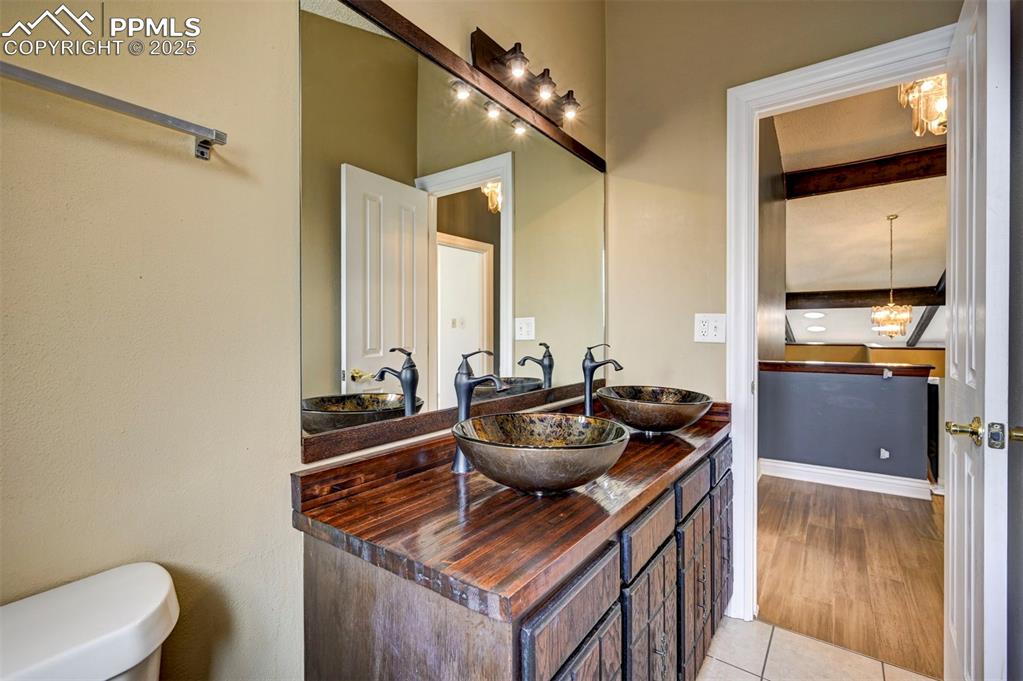 Bathroom featuring double vanity, beam ceiling, tile patterned flooring, and a chandelier