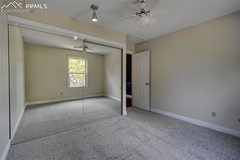 Unfurnibedroom featuring carpet floors, a textured ceiling, a closet, and a ceiling fan