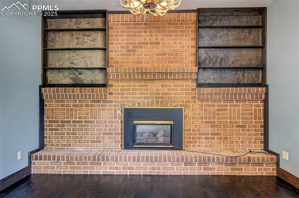 Detailed view of a chandelier, a fireplace, and wood finished floors