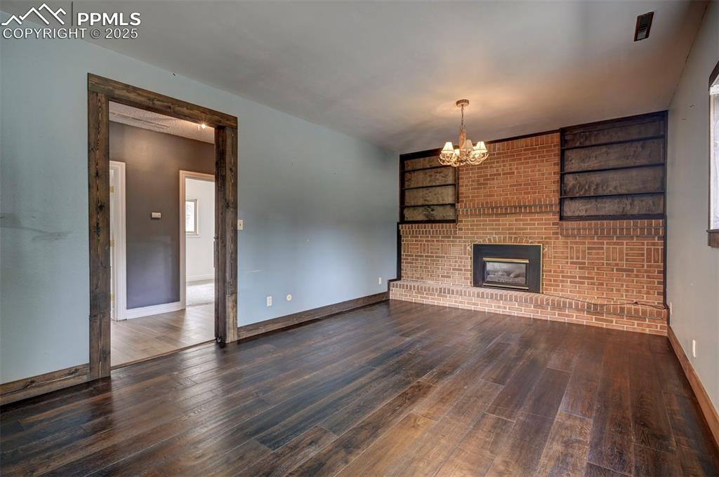 Unfurnished living room with wood finished floors, a chandelier, and a fireplace