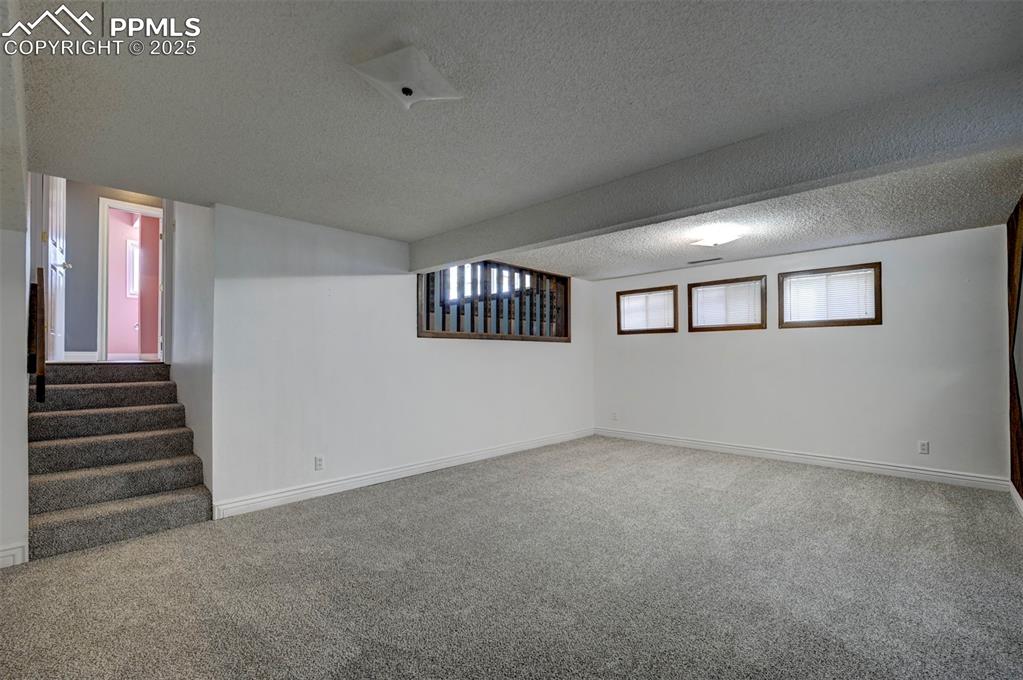 Basement with carpet, a textured ceiling, and stairs