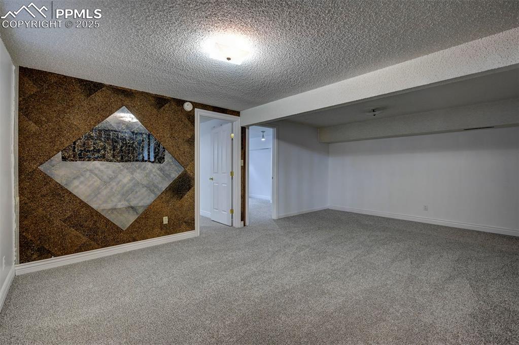 Finished below grade area with a textured ceiling and carpet flooring