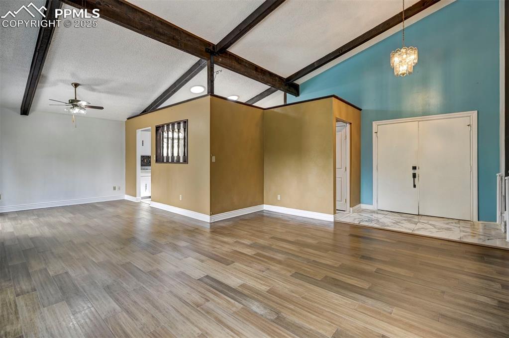 Unfurnished living room featuring a ceiling fan, a chandelier, wood finished floors, and a textured ceiling