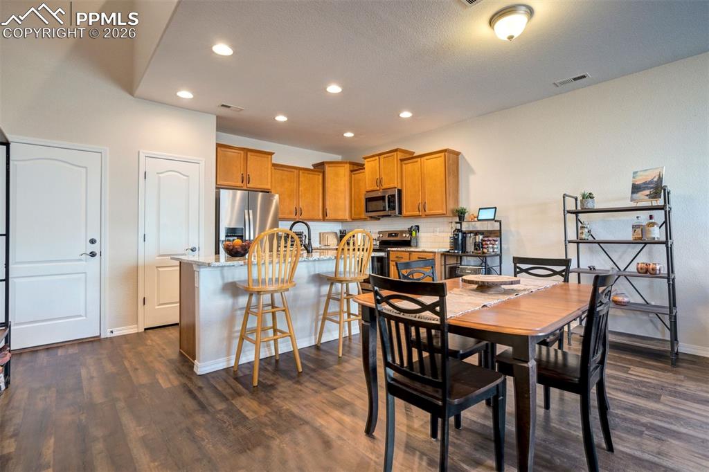 Dining area open to the kitchen showing the breakfast bar, the pantry door and the door to the oversized 2 car garage.