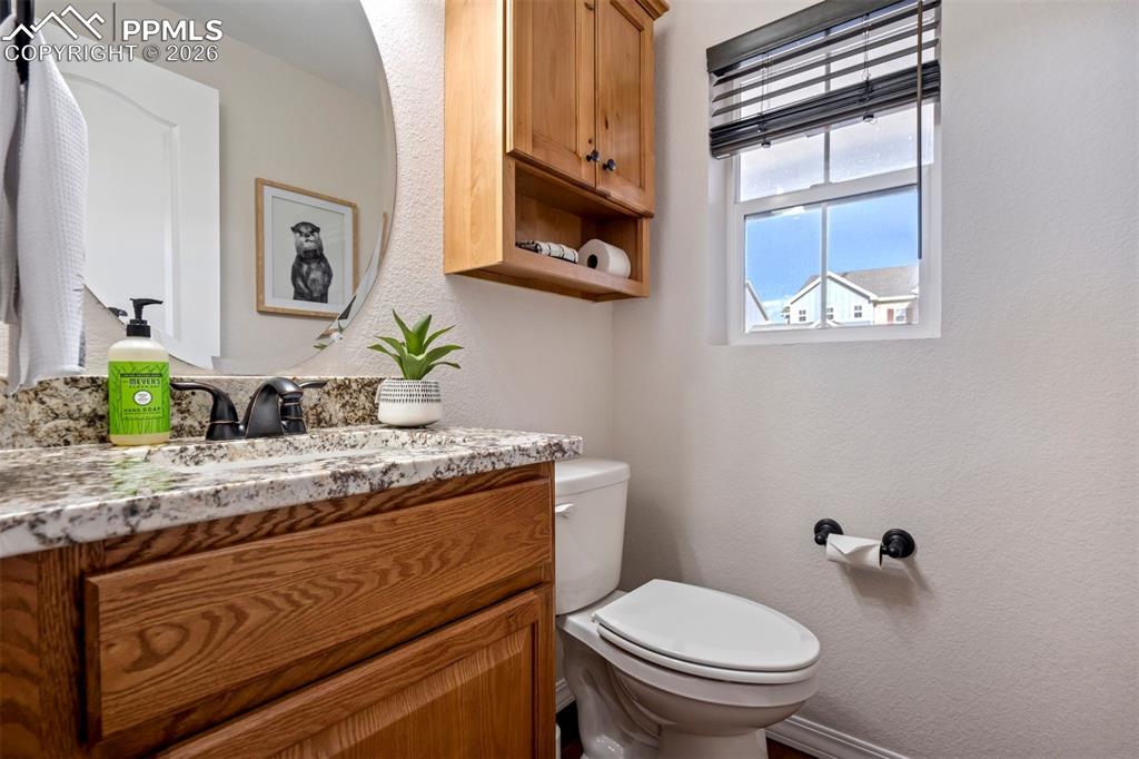 Half bathroom with vanity with stone countertop.