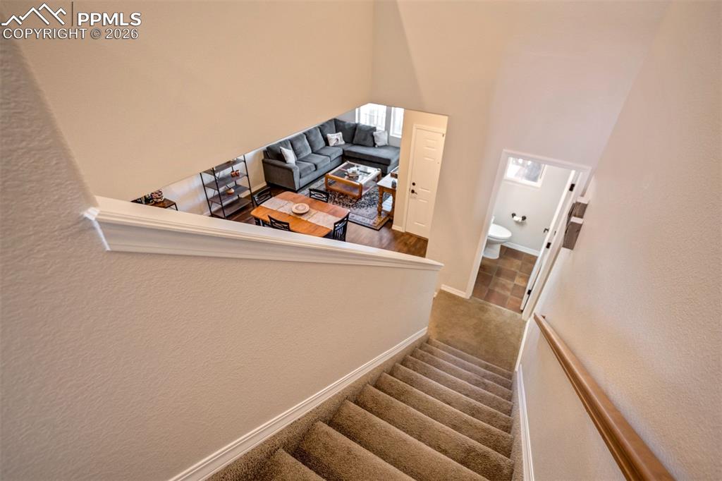 Stairway featuring carpet floors.  Powder room with tile floor. 
