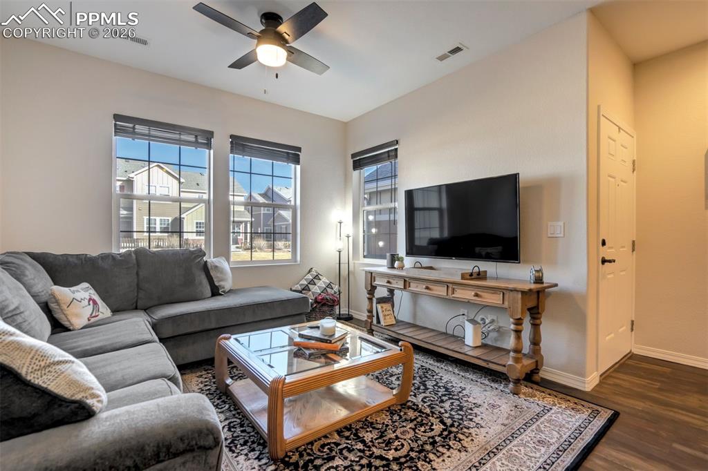 Light filled living area with fan and attractive wood flooring.  