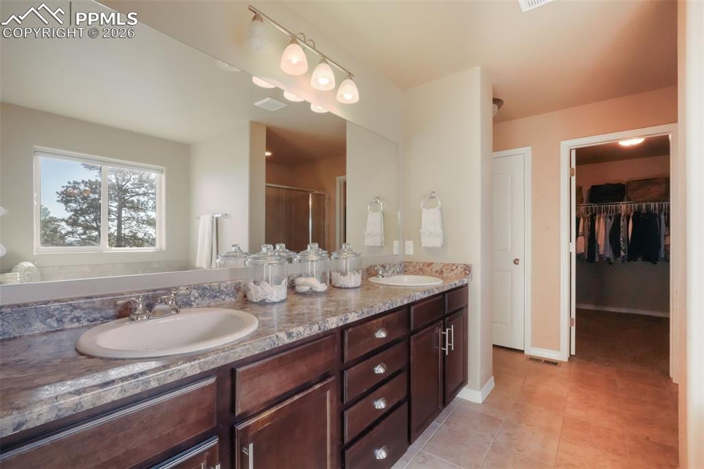Primary bathroom with dual vanities, soaking tub, large shower, and walk in closet