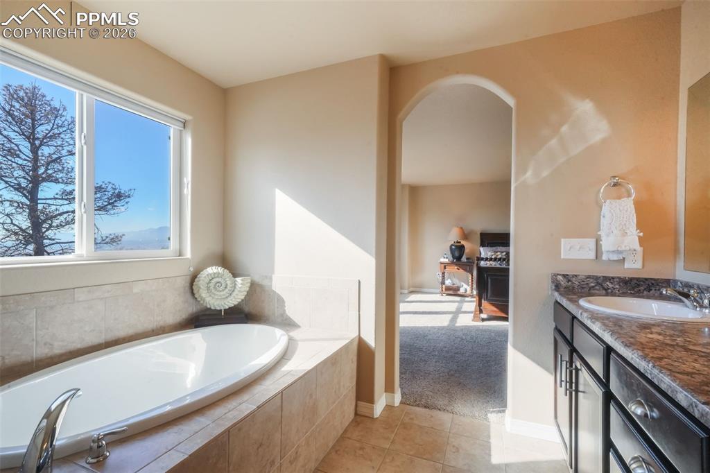 Primary bathroom with dual vanities, soaking tub, large shower, and walk in closet