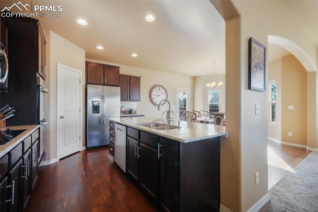 Kitchen with stainless steel appliances, granite counters, double wall ovens, cooktop, bar seating and dining area