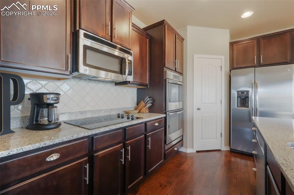 Kitchen with stainless steel appliances, granite counters, double wall ovens, cooktop, bar seating and dining area