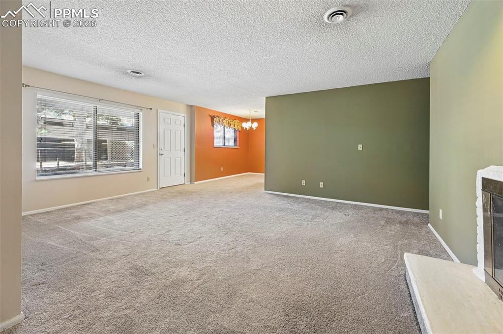 Unstaged living room and dining room, featuring fireplace 