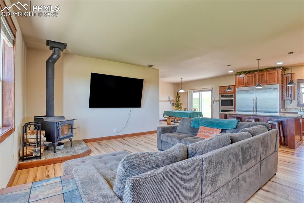 Living area with a wood stove, light wood finished floors, and pool table