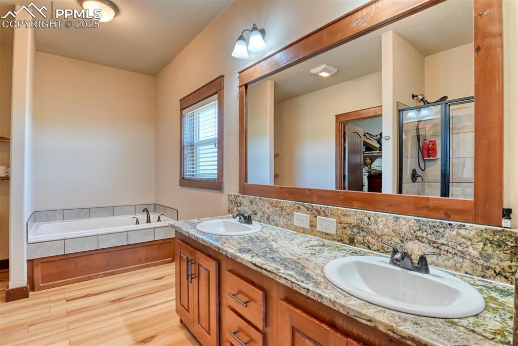 Full bath with LVT wood style flooring, a garden tub, and double vanity