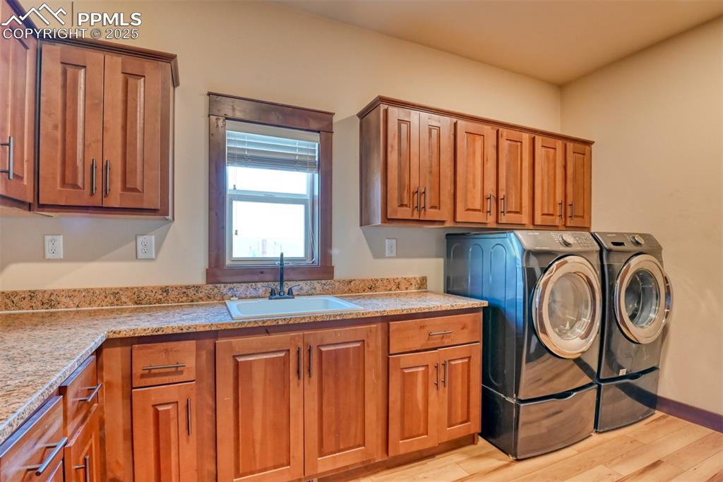 Washroom featuring cabinet space, washer and clothes dryer, and LVT wood style flooring