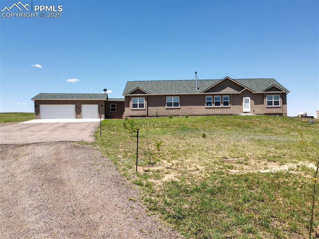 Single story home featuring asphalt driveway, stucco siding, and a front lawn