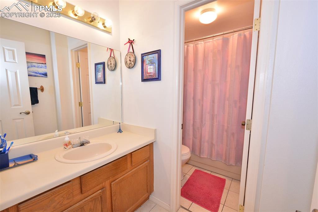 Full bathroom featuring shower / bath combo with shower curtain, tile patterned floors, vanity, and toilet