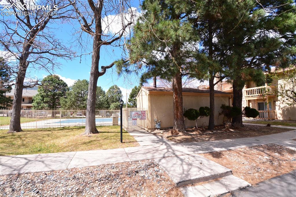 View of front of property featuring fence, a front lawn, and a community pool
