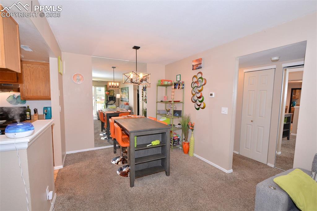 Dining space with light colored carpet, baseboards, and a notable chandelier