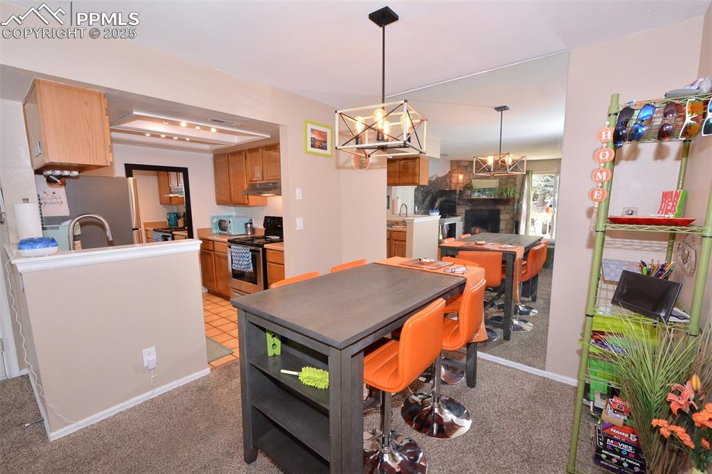 Dining area featuring light carpet, baseboards, and a notable chandelier