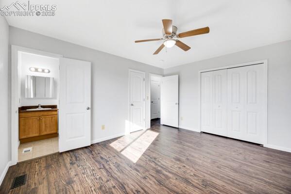 Unfurnished bedroom featuring dark wood-type flooring, ceiling fan, a closet, and ensuite bath