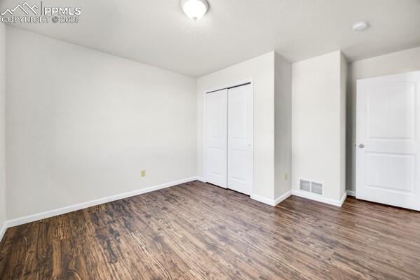Unfurnished bedroom with a closet and dark wood-style floors