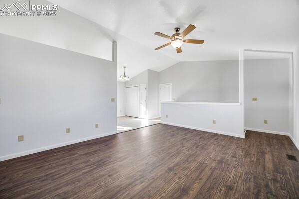 Unfurnished living room with a chandelier, dark wood finished floors, lofted ceiling, and ceiling fan
