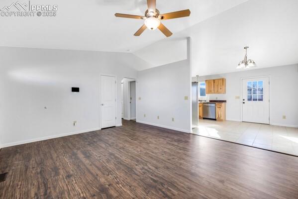 Unfurnished living room featuring dark wood-style flooring, ceiling fan, arched walkways, a chandelier, and high vaulted ceiling