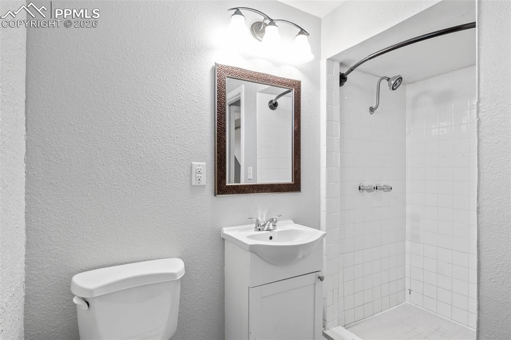 Bathroom featuring vanity, a textured wall, and a shower stall
