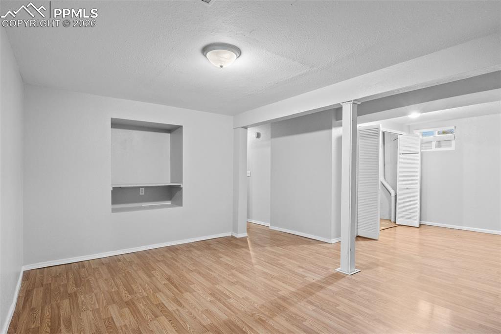 Finished basement featuring a textured ceiling and light wood-type flooring