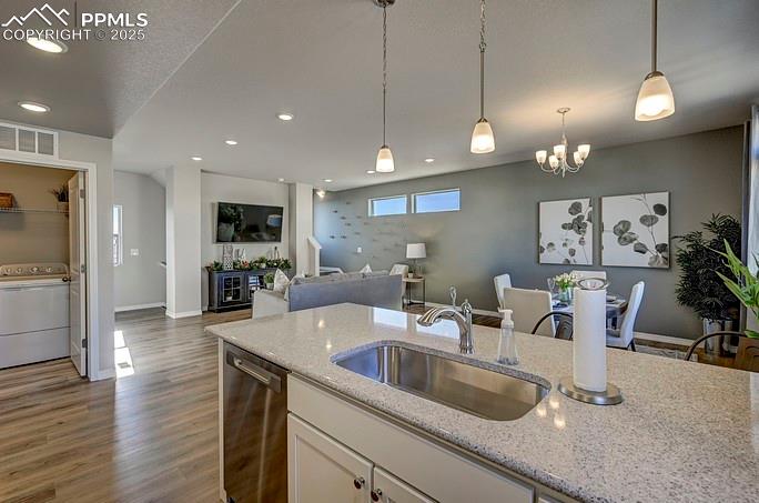 Kitchen with washer / dryer, white cabinetry, pendant lighting, dishwasher, and recessed lighting