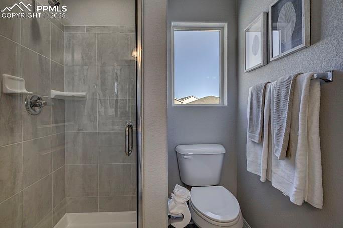 Full bathroom featuring a stall shower and toilet