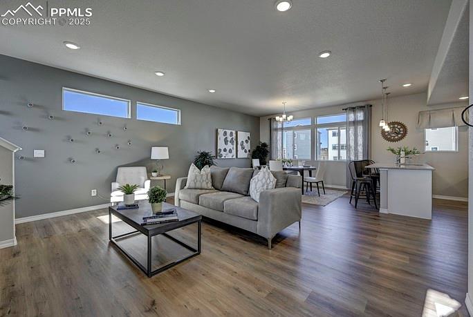 Living area featuring a chandelier, dark wood-style flooring, recessed lighting, and a textured ceiling