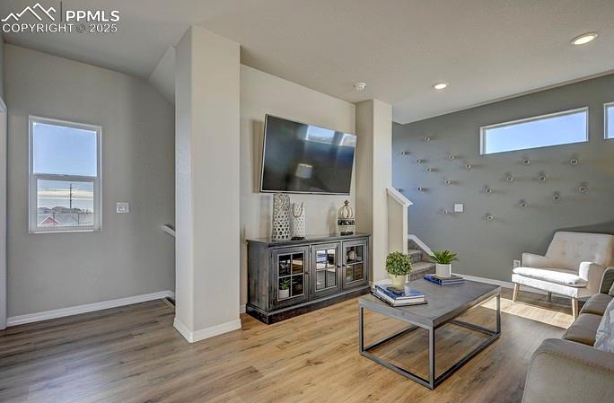 Living room with wood finished floors, stairway, and recessed lighting