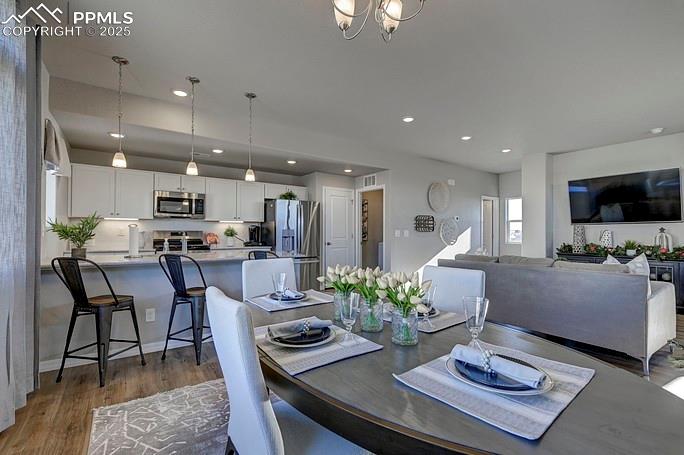 Dining space featuring dark wood-style flooring, recessed lighting, and a chandelier