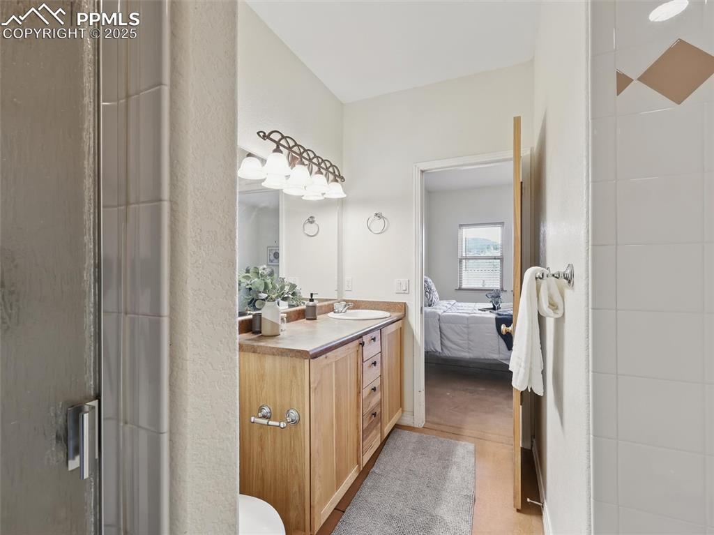 Ensuite bathroom with vanity, a shower stall, and light wood-style flooring