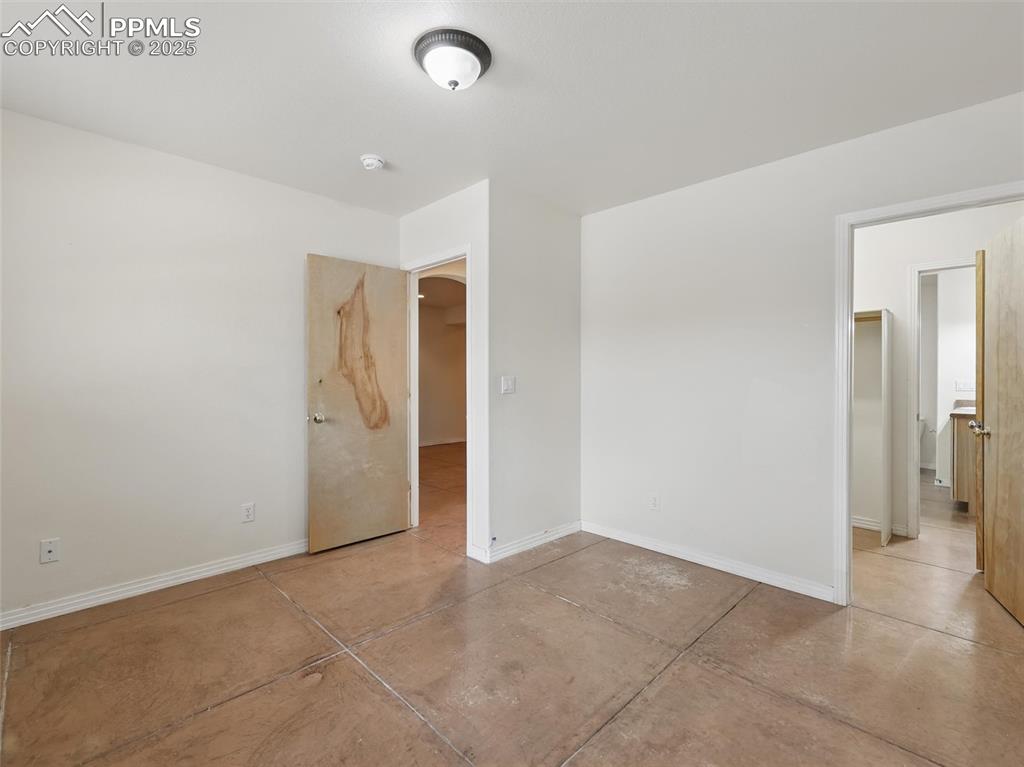 Unfurnished bedroom featuring baseboards and concrete flooring