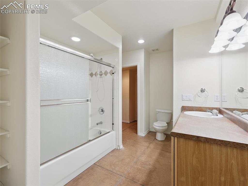 Bathroom featuring light tile patterned flooring, bath / shower combo with glass door, vanity, and recessed lighting