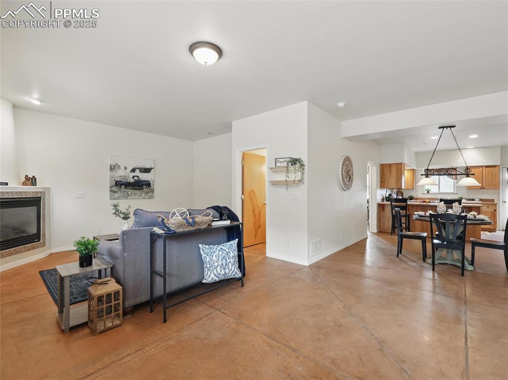 Living area with finished concrete flooring, recessed lighting, and a tile fireplace