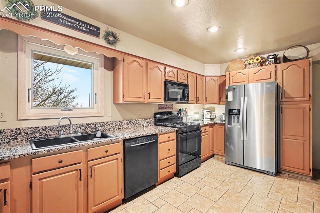 Kitchen featuring black appliances, light stone countertops, and recessed lighting